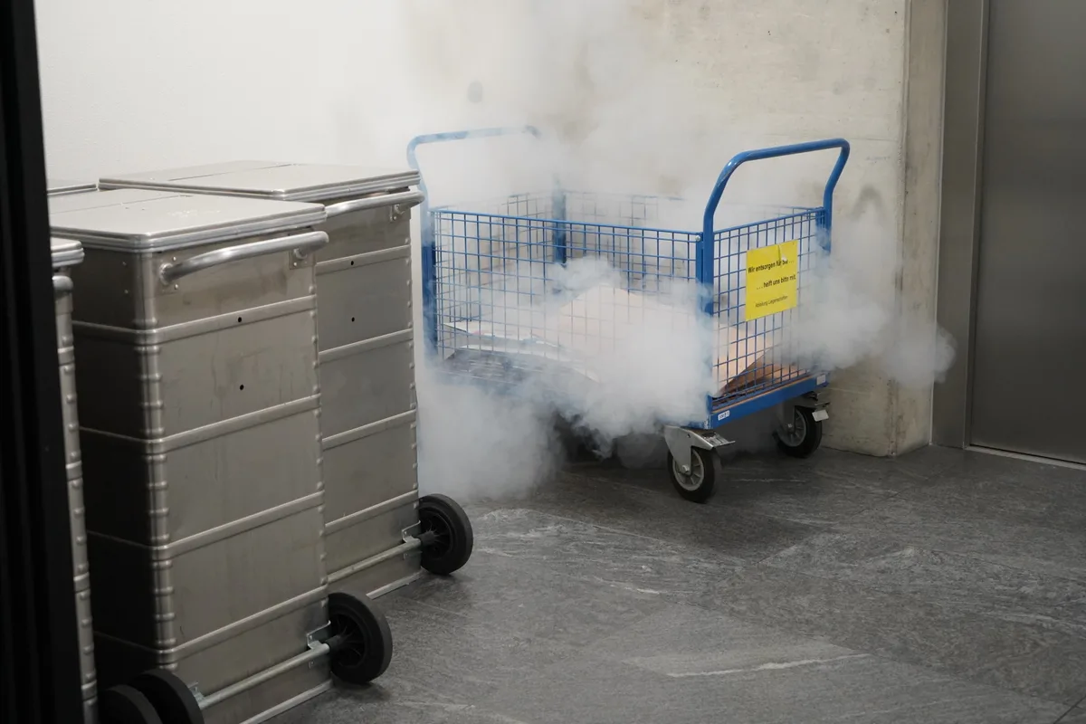 Disco-Nebel strömt hinter einem Rollwagen mit Kartons hervor.
