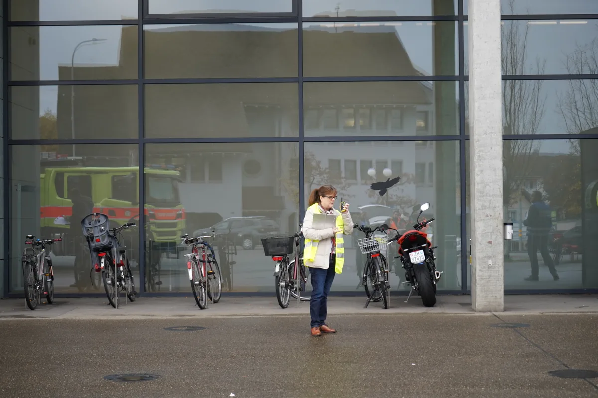 Eine Frau mit Warnweste steht vor der Glaswand vom Stadthaus.