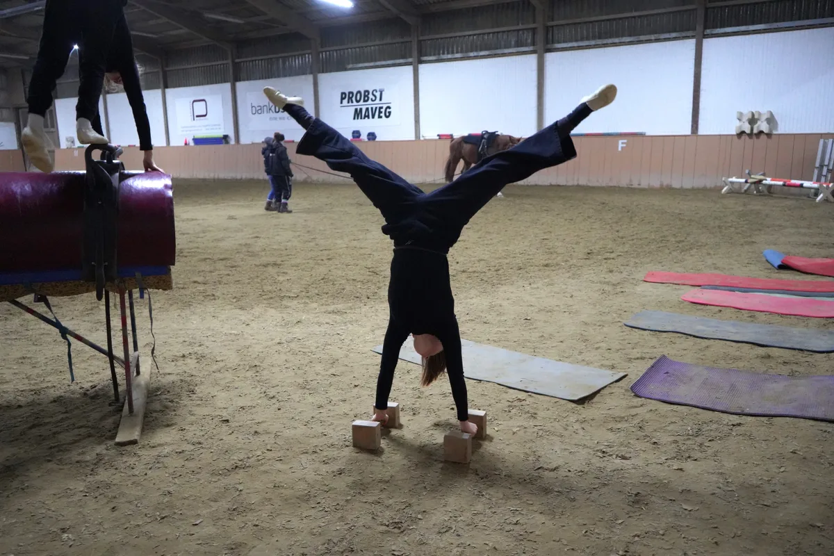 Zwei Sportlerinnen machen in der Halle auf Geräten Turnübungen.
