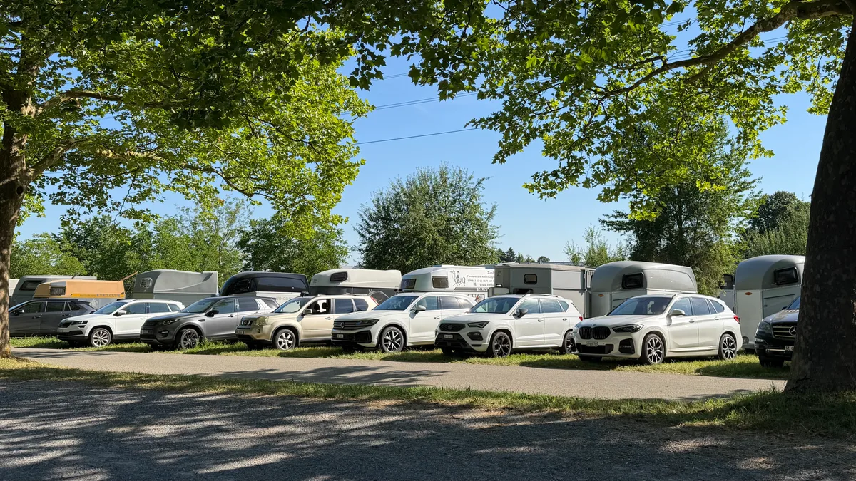 Ein SUV mit Anhänger reiht sich an den anderen. Der Parkplatz vor dem Schützenhaus ist voll. Blick auf viele SUVs mit Anhänger.