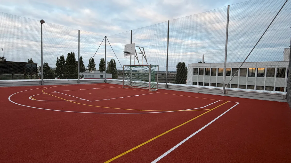 Bei gutem Wetter kann auf diesem erhöhten Sportplatz mit guter Aussicht gespielt werden. Sportplatz auf dem Dach.