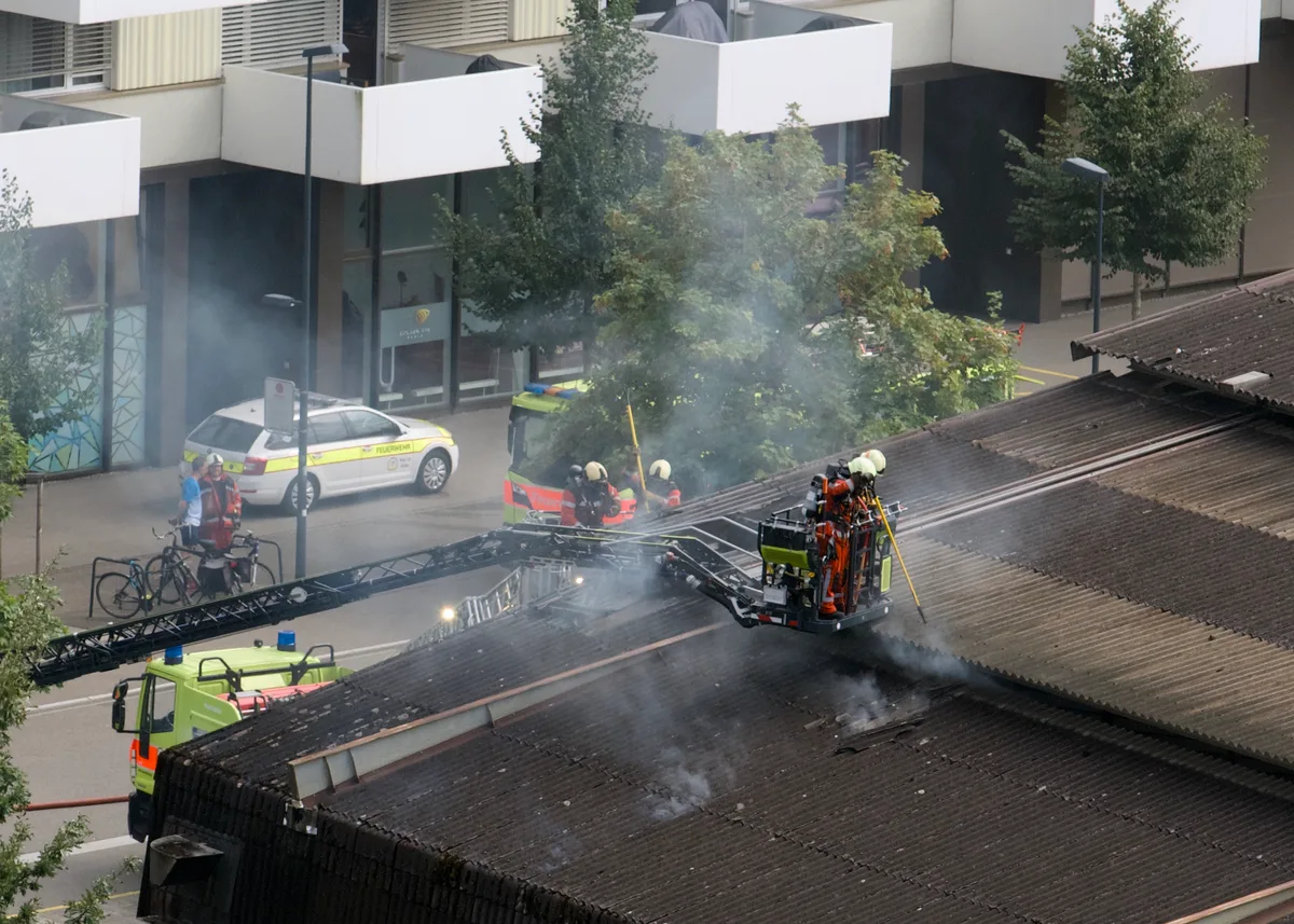 Man sieht Feuerwehrleute auf einer Drehleiter beim Löschen eines Brandes.