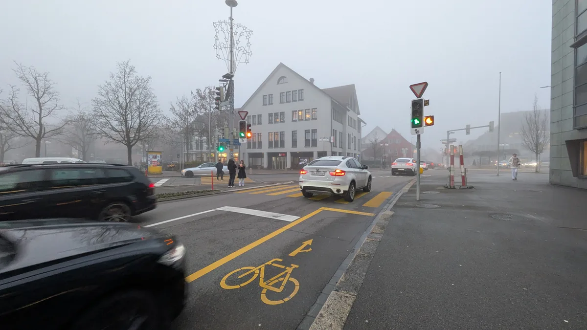 Man sieht eine Kreuzung in einer Innenstadt mit fahrenden Autos.