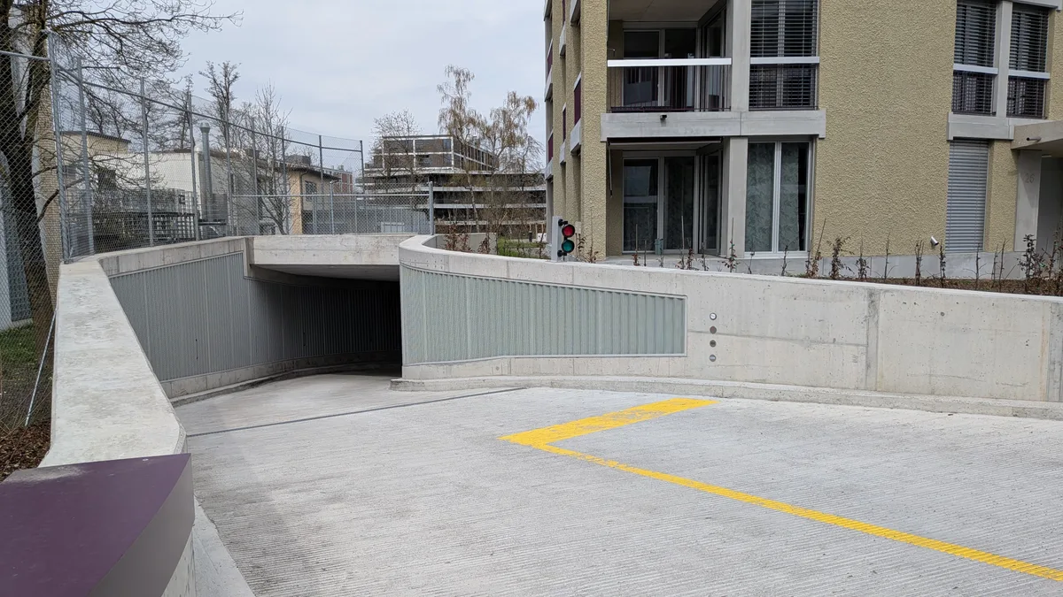 Bauherren müssen weniger Parkplätze bauen, wenn sie das wollen. Der Gemeinderat lockerte die entsprechende Verordnung. Garagenabfahrt in ein Mehrfamilienhaus.