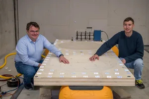 16375989-5 Stefan Schoenwald (links) und Sven Vallely beim Modell der schallschluckenden Holzdecke. Die ins Holz eingefrästen Vertiefungen sind «akustische Schwarze Löcher».