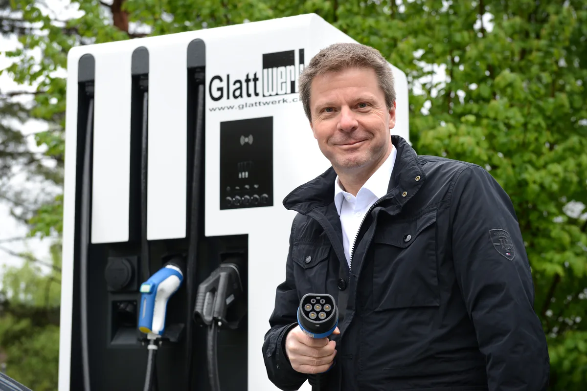 Ein Mann mit einem Ladekabel für E-Autos in der Hand. 