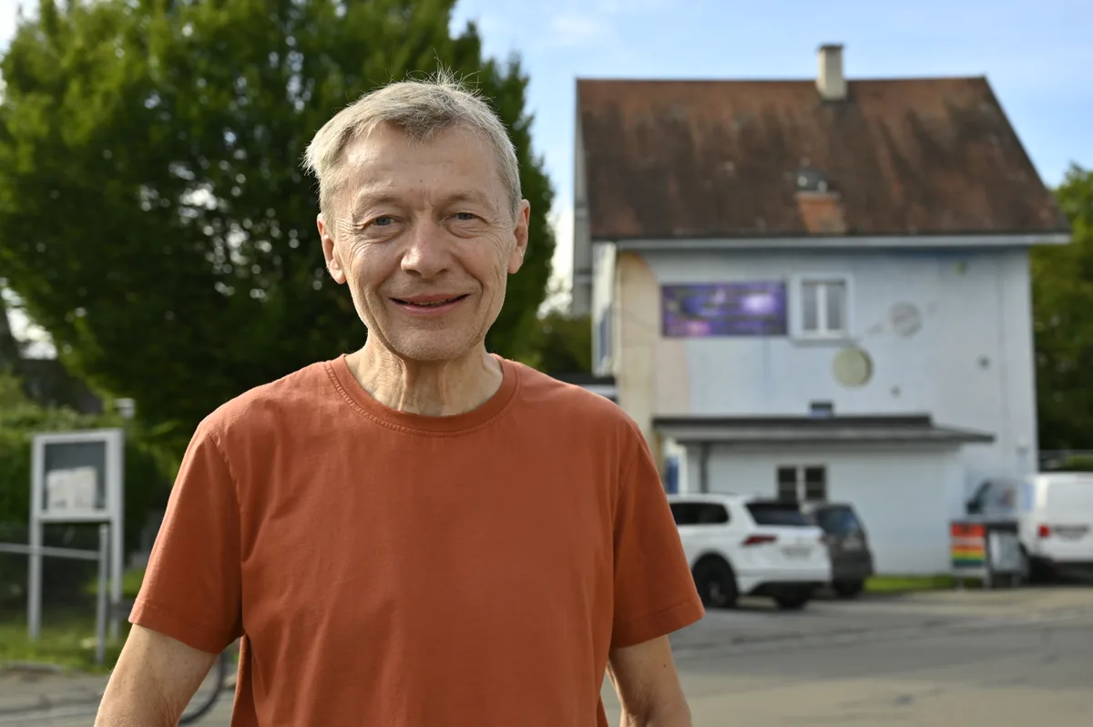 Porträtaufnahme eines Mannes, im Hintergrund ein Jugendhaus. 