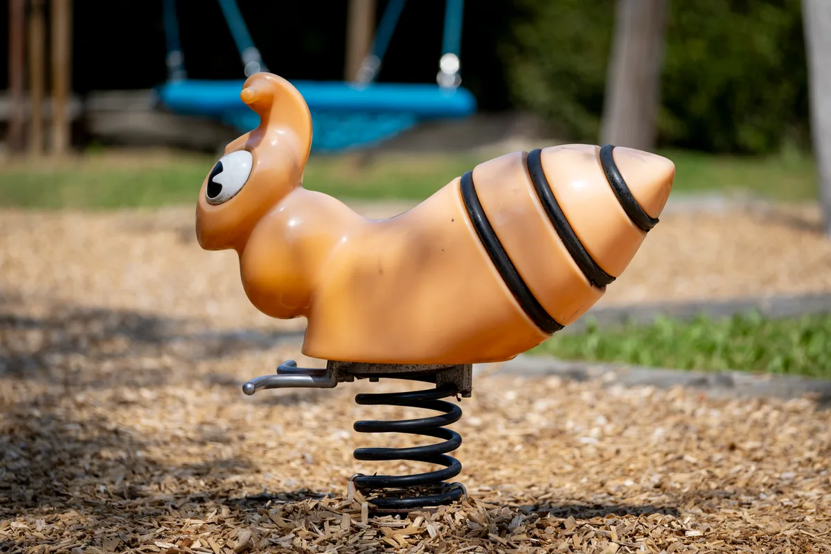 Wurm? Insekt? Alien? Egal, auch auf diesem Ding kann man schaukeln. Spielzeugtier zum Schaukeln auf einem Spielplatz.