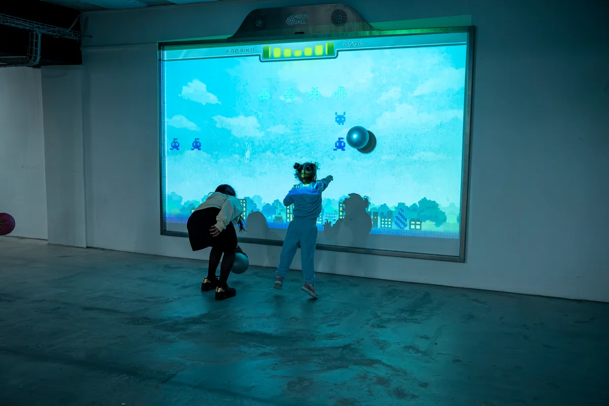 In der Fabrik 11 ist der Sportunterricht auch mal digital und interaktiv. Zwei Kinder werfen Bälle.