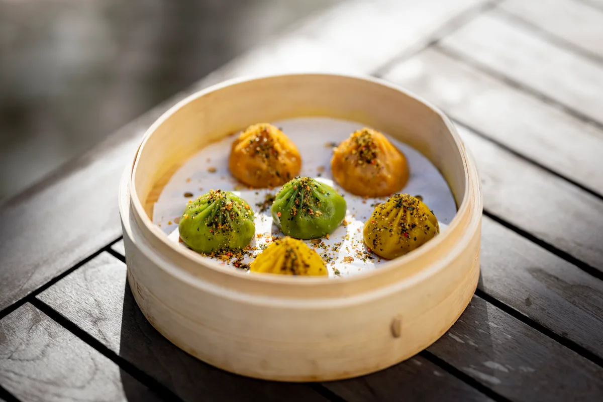 Sechs gedämpfte Dumplings in einem Bambuskorb.