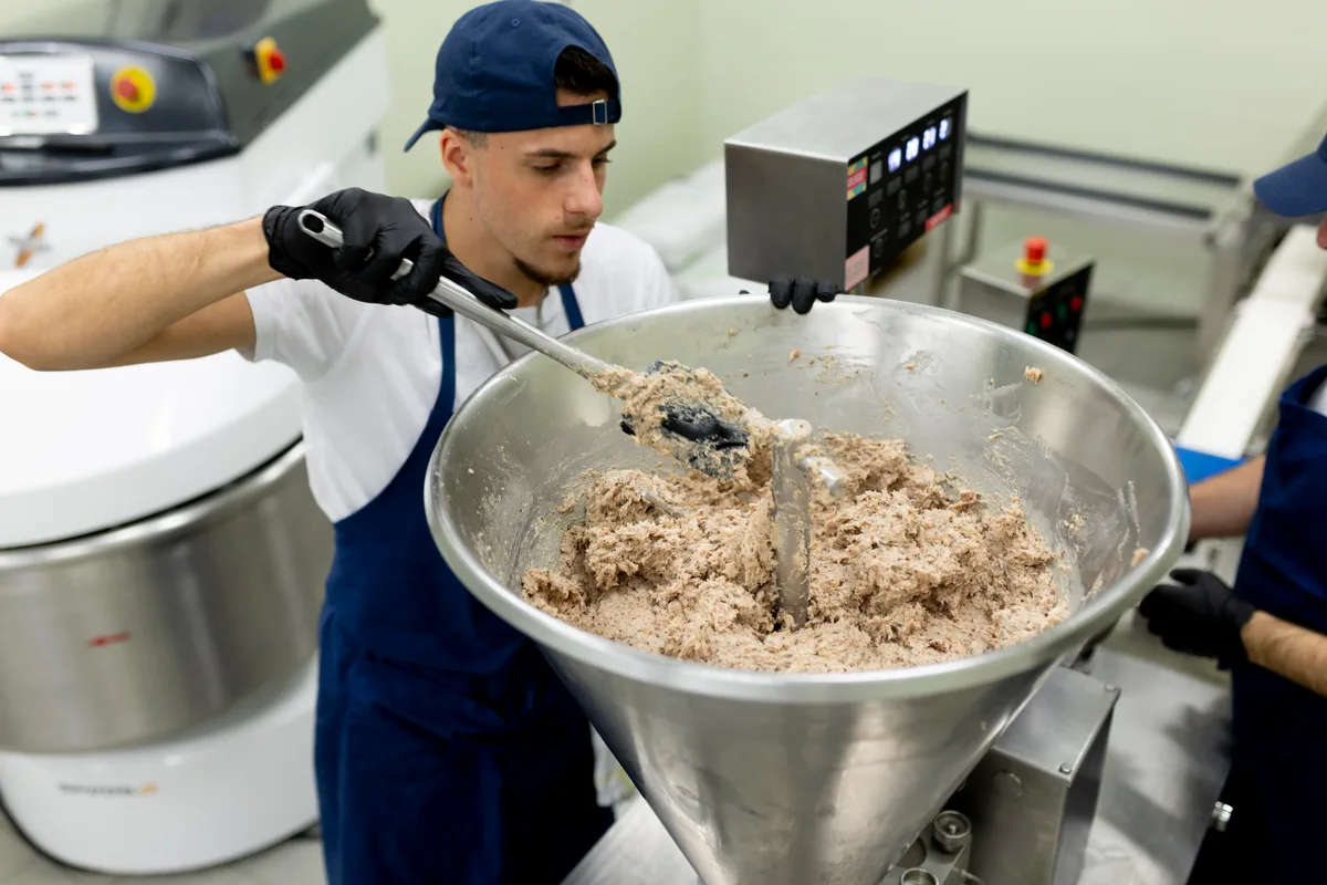 Ein Mann stopft Dumpling-Füllung in einen grossen Trichter.