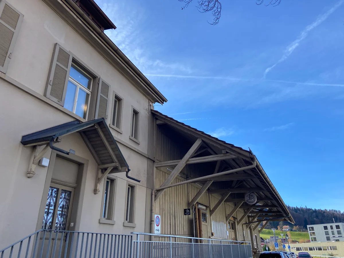 Ein Gebäude und eine Holzhalle von aussen.
