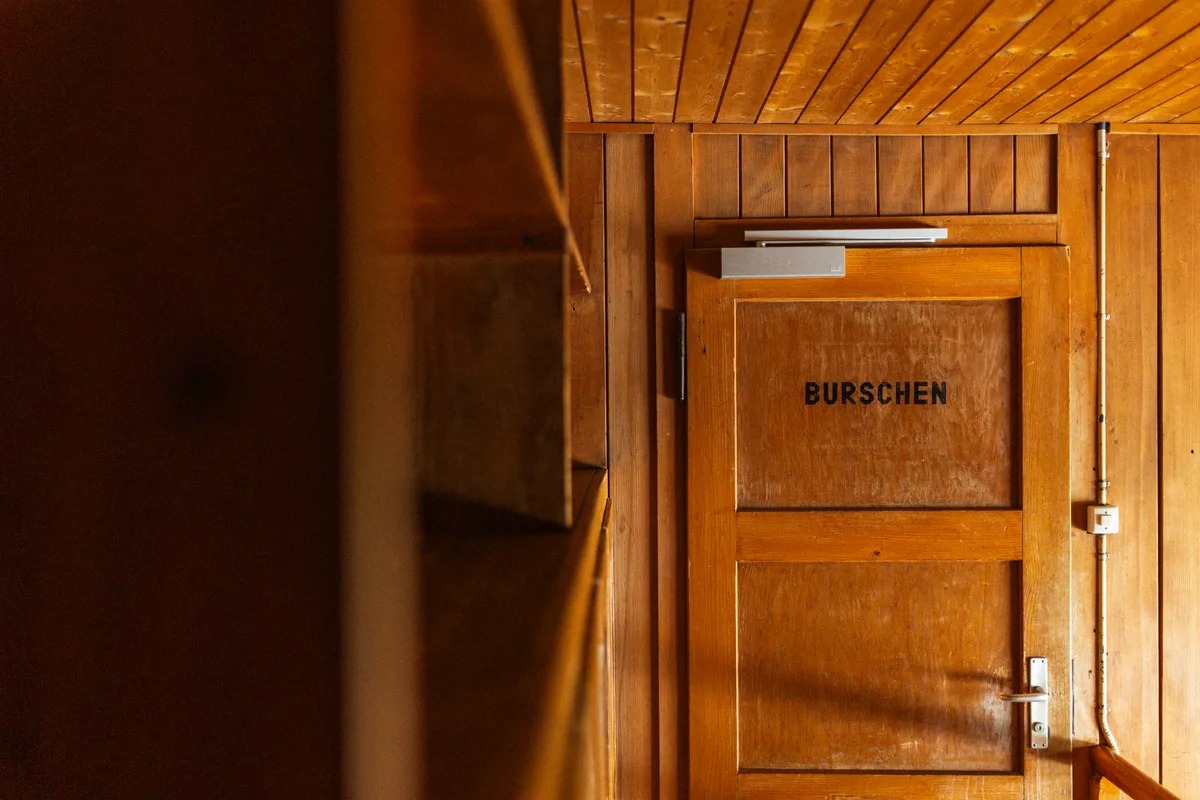 Der Massenschlag ist nach Geschlechtern getrennt. Die Tür zum Massenschlag: «Burschen» steht auf der Tür.