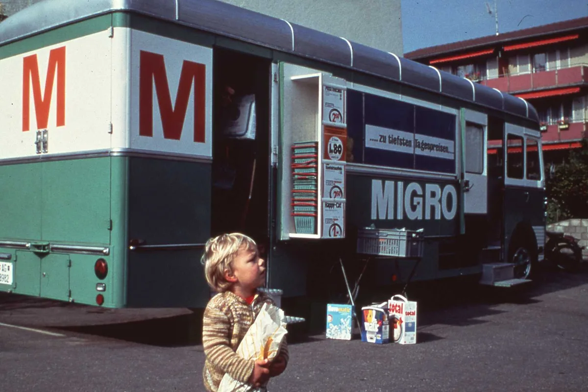 Ein Kind vor einem grün-weissen Lastwagen.