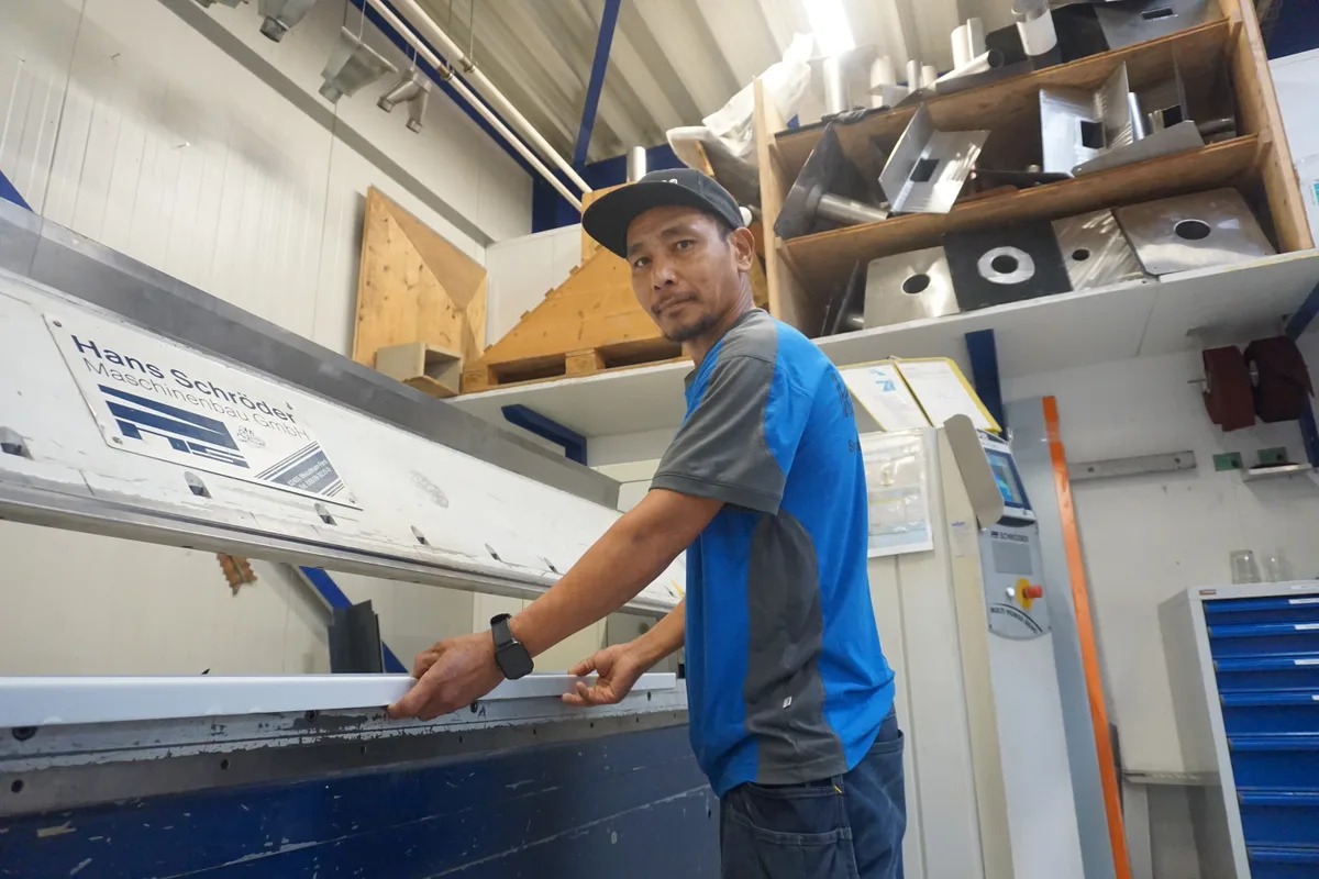 Mann mit Käppi an Maschine.