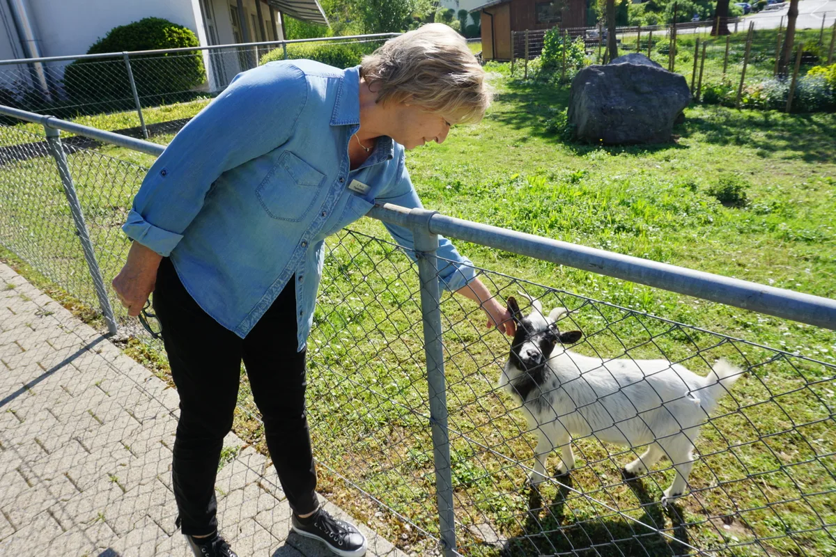 Frau streichelt Ziege
