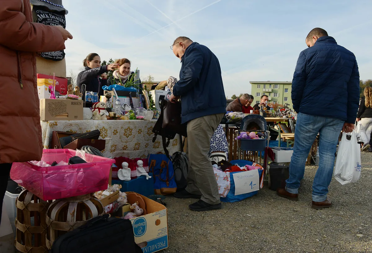 Gerümpel und Menschen an einem Flohmarkt im Freien.