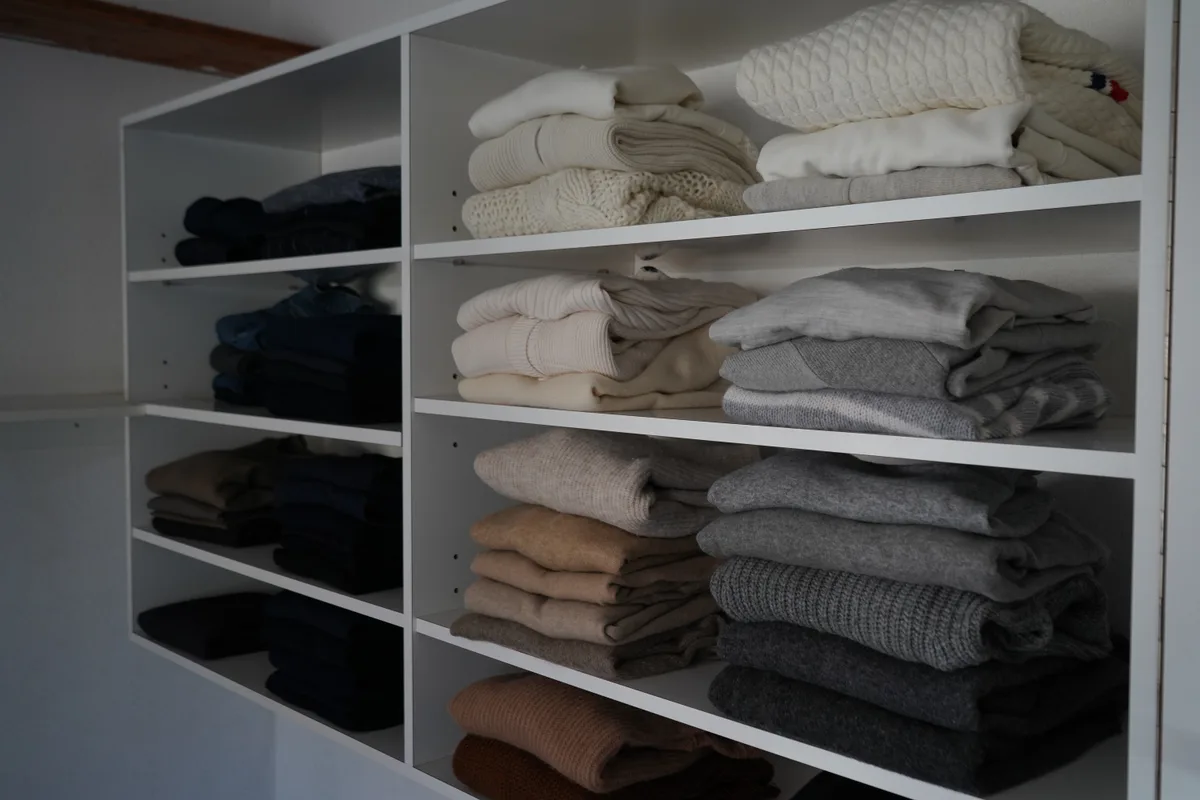 Schön aufgestappelte Pullover in einem Gestell.