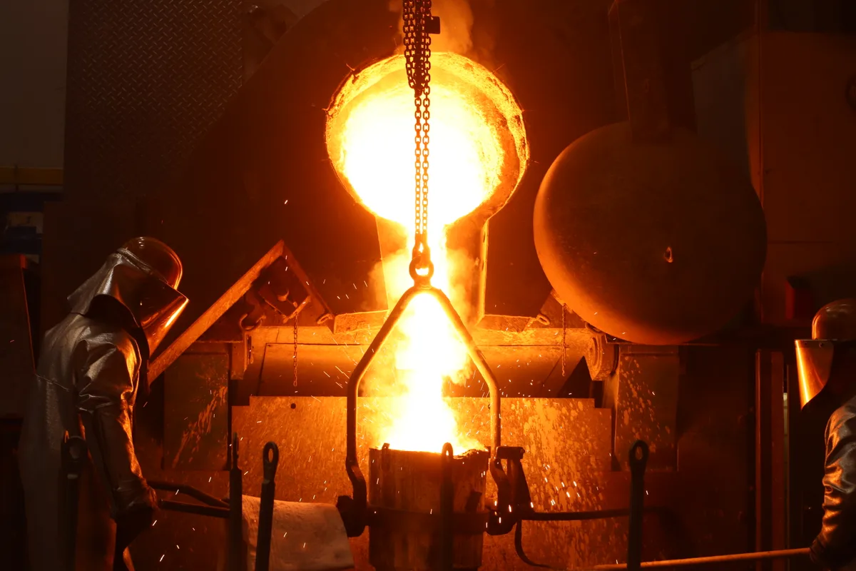Arbeiter giessen flüssiges Metall in Gussformen.