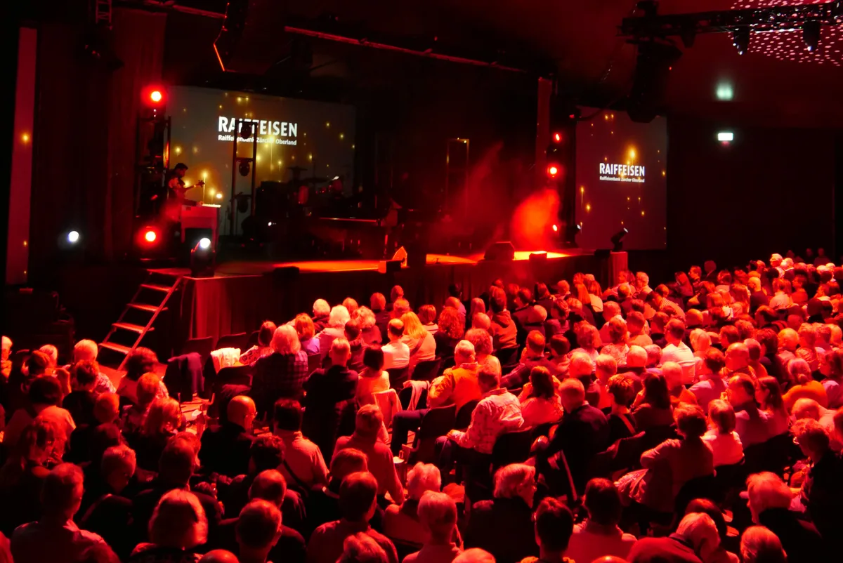 Zahlreiches Publikum im Saal folgt einer Darbietung des Pianoduos Chris und Mike. Der Saal ist in rotes Licht getaucht.