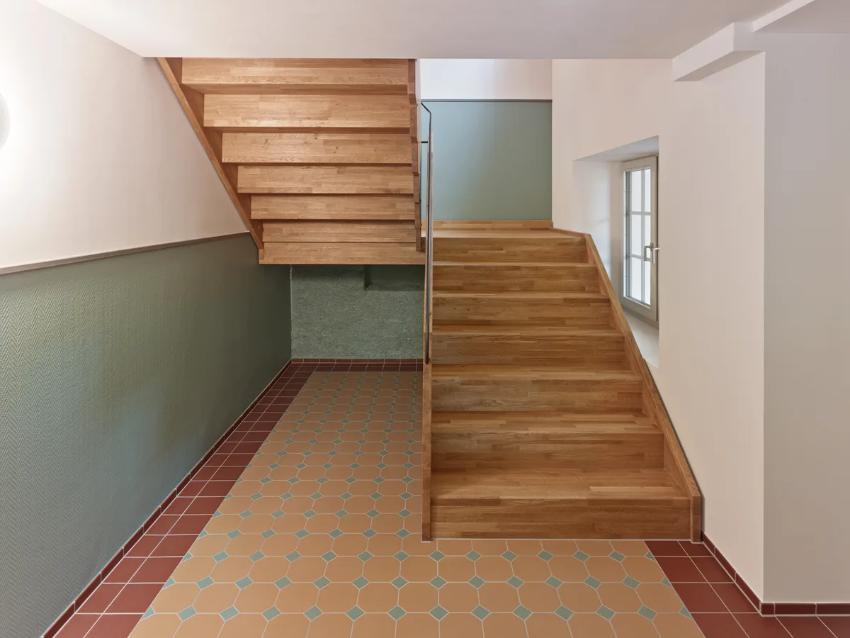 Im Haus gibt es eine 2½-Zimmer-Wohnung sowie drei 3½-Zimmer-Wohnungen. Eine Innenansicht des sanierten Hauses zur Platte in Wald. Man sieht ein Treppenhaus mit einer Holztreppe.