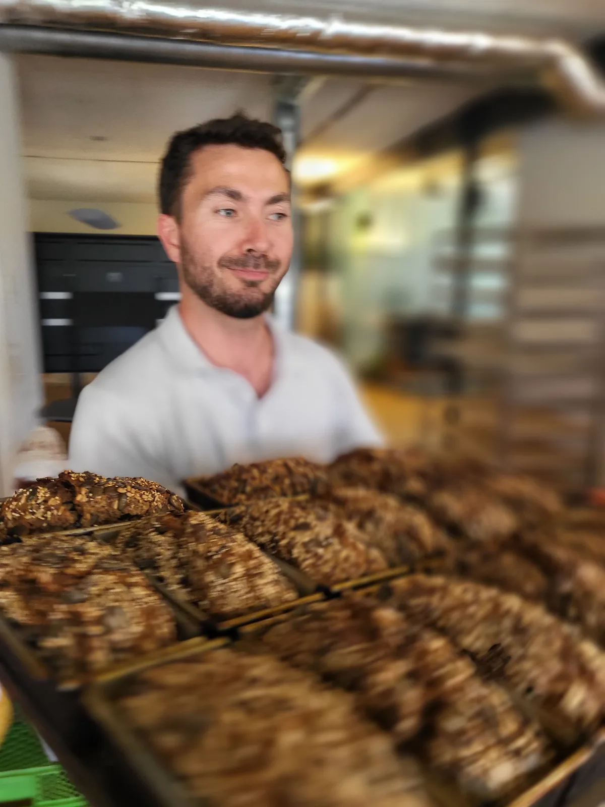 Ein Mann hält ein Blech mit frisch gebackenen Sauerteigbroten.