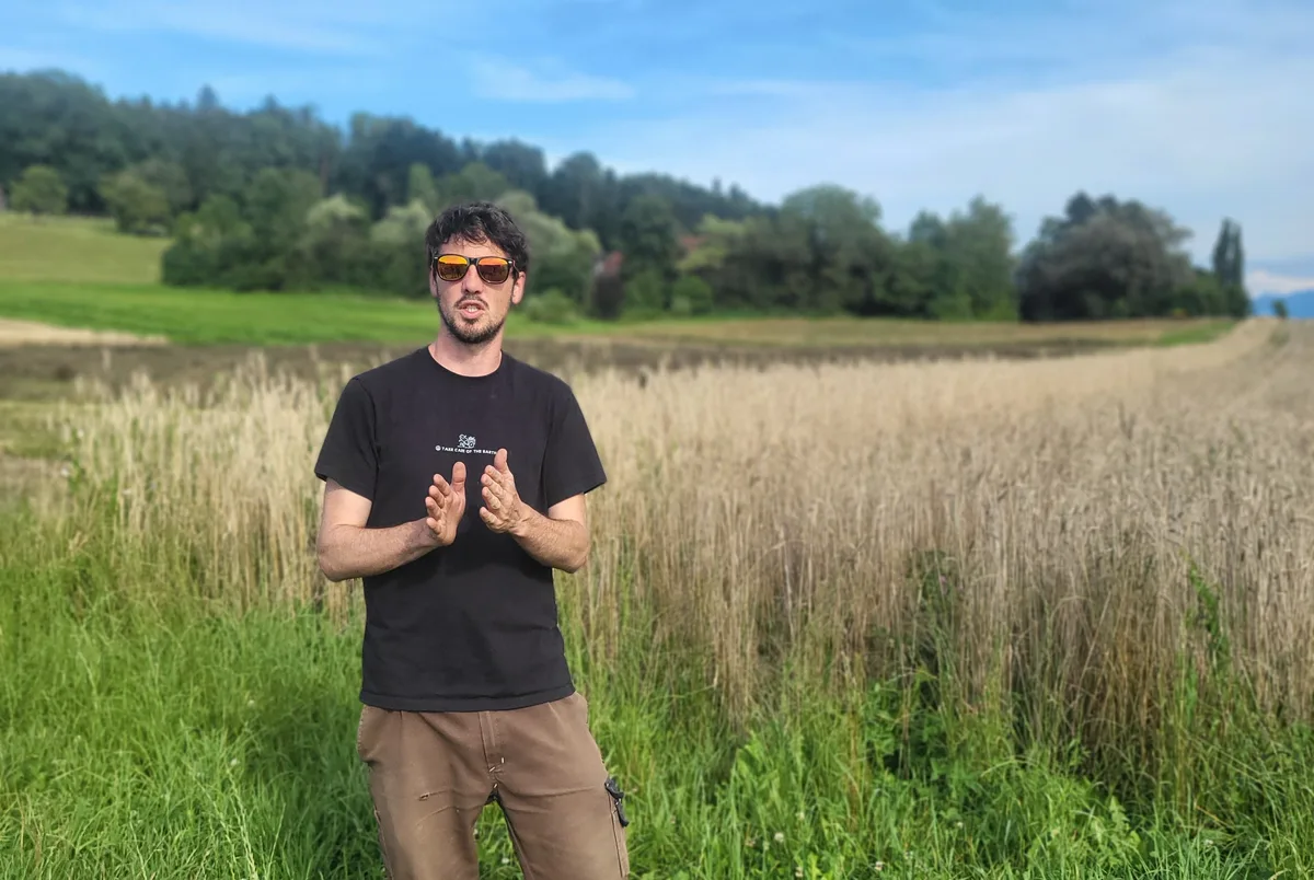 Ein Bauer steht neben seinem Weizenfeld.