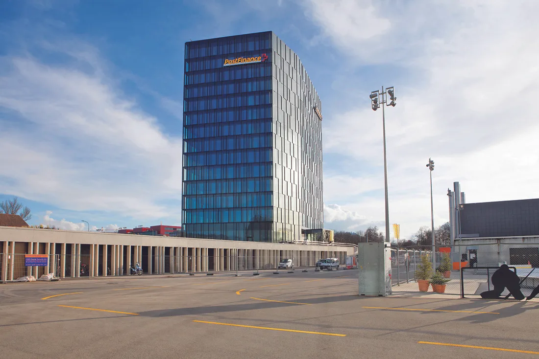 Der Hauptsitz der Postfinance in Bern. Ein modernes Hochhaus mit gelbem Schriftzug.