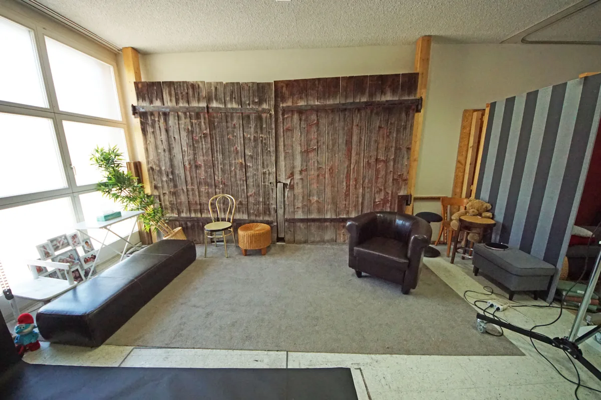 Blick ins Fotostudio von Foto Müller: eine Holzwand mit Möbeln davor.