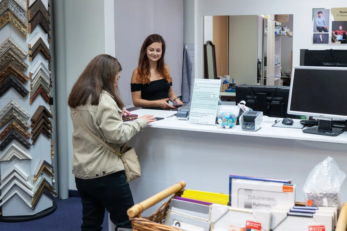 Blick in das Geschäft von Foto Müller. Zwei Frauen stehen an einem Tresen und unterhalten sich.