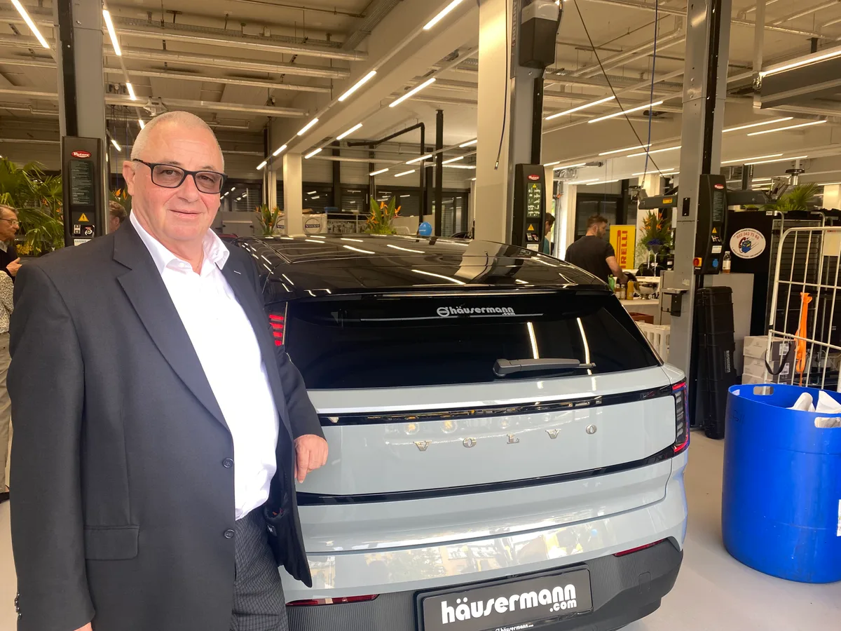 Ein Mann im Anzug steht vor einem Auto der Marke Volvo.