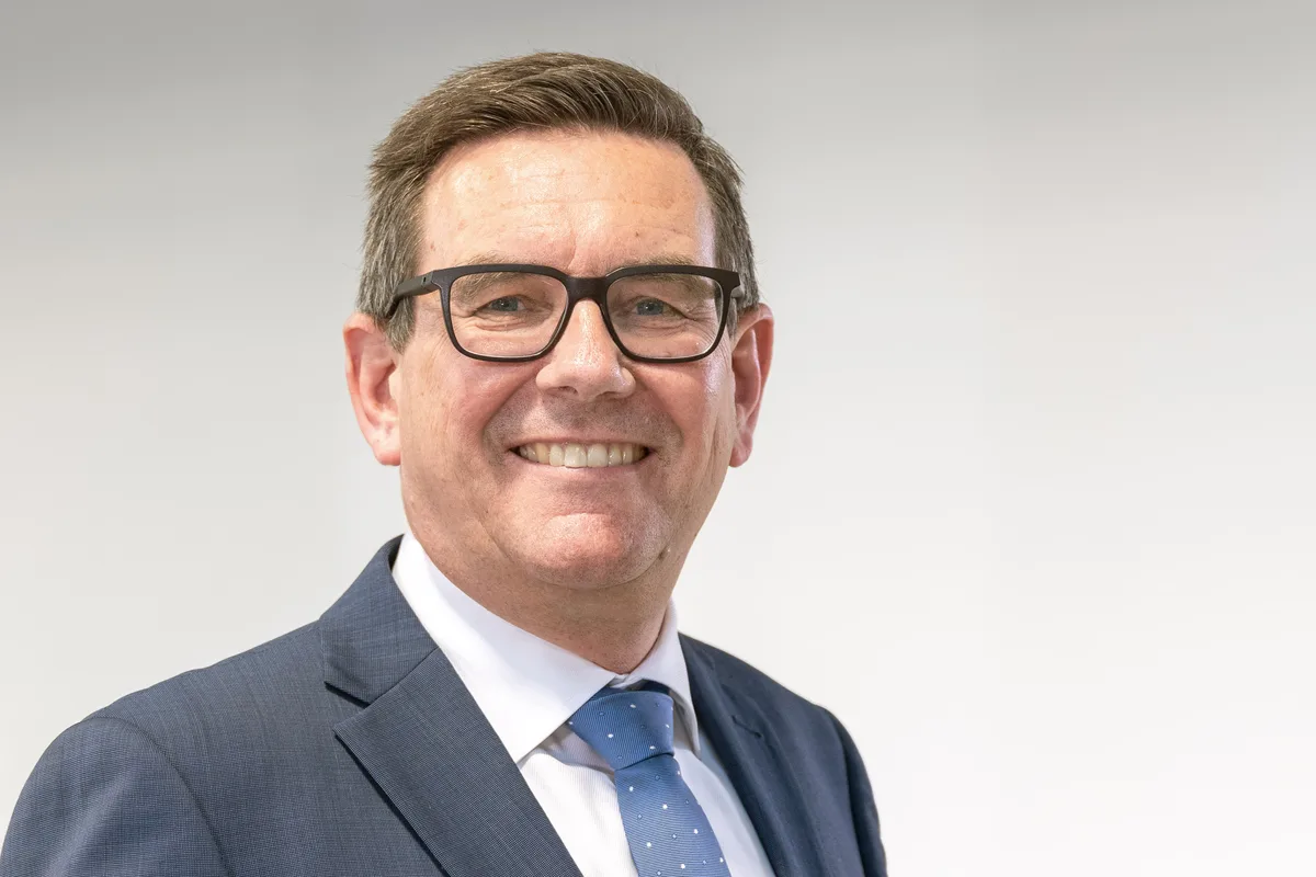 Porträtbild eines Mannes mit Brille, in Anzug mit Krawatte.