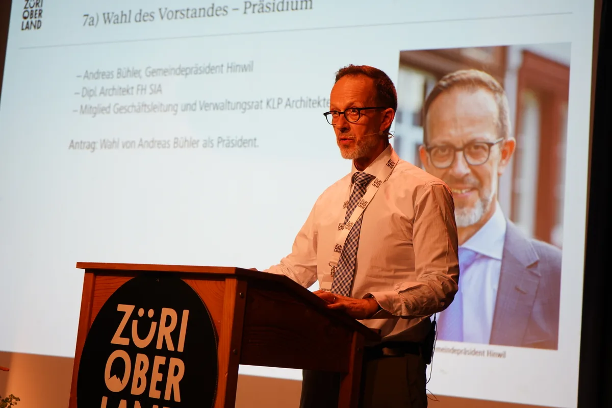 Ein Mann in weissem Hemd und mit Krawatte steht hinter einem Rednerpult.