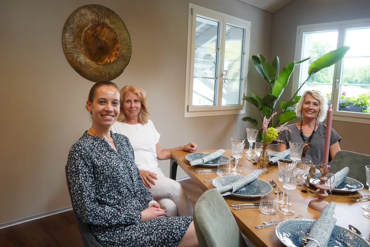 Drei Frauen sitzen an einem schön gedeckten Tisch.