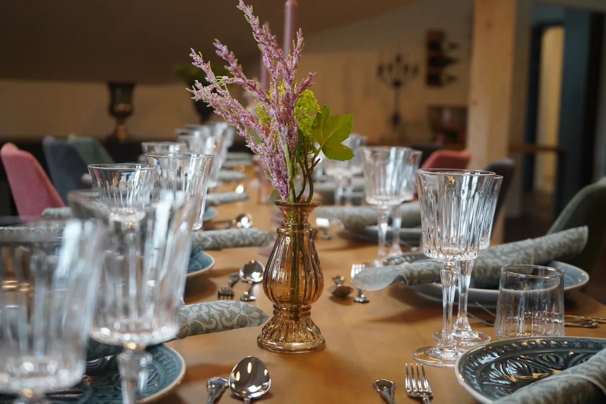 Blick in einen Raum mit einem reichhaltig dekorierten langen Esstisch.