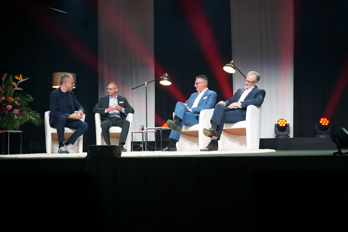 Vier Männer sitzen bei der Informationsveranstaltung der Raiffeisenbank Zürcher Oberland auf einer Bühne.