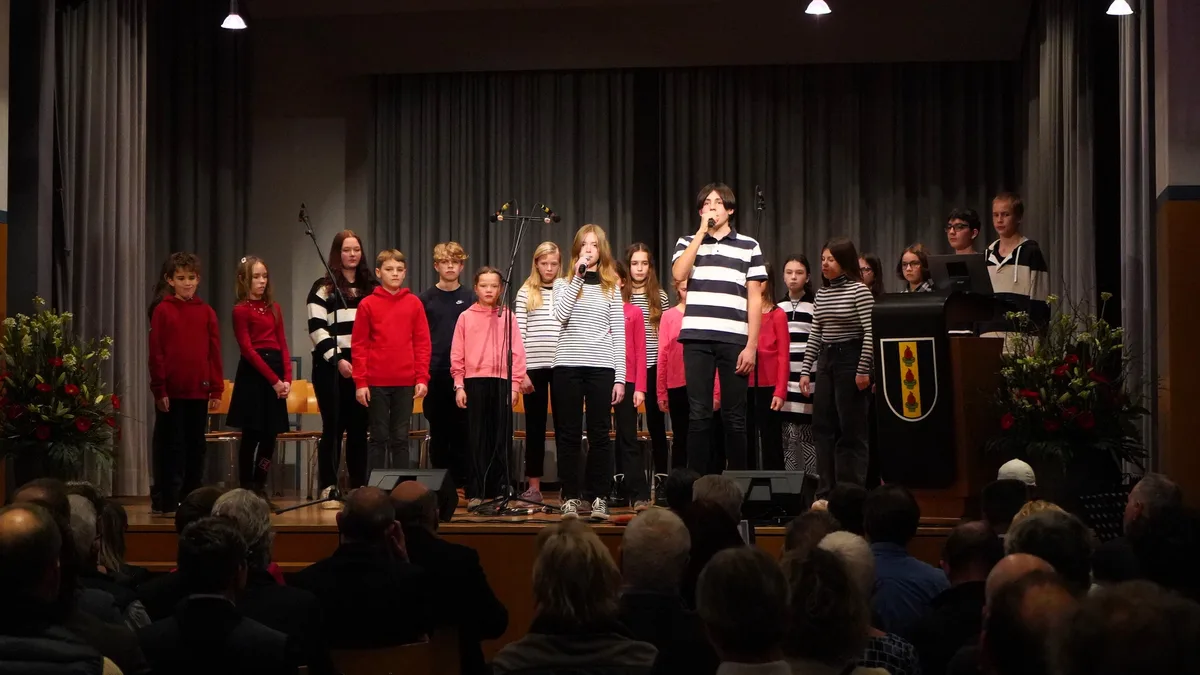 Kinder singen auf einer Bühne.