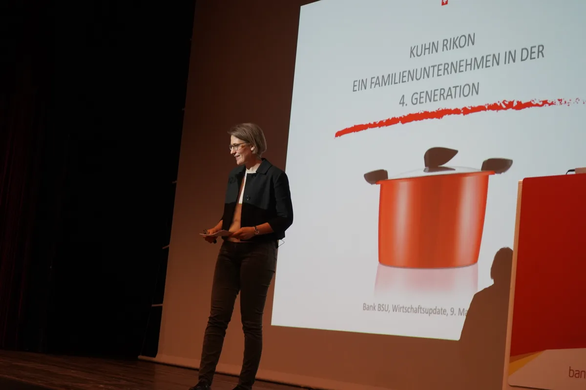 Dorthee Auwärter, VR-Präsidentin von Kuhn Rikon, steht auf der Bühne. Im Hintergrund wird ein Kochtopf von Kuhn Rikon auf die Leinwand projiziert.