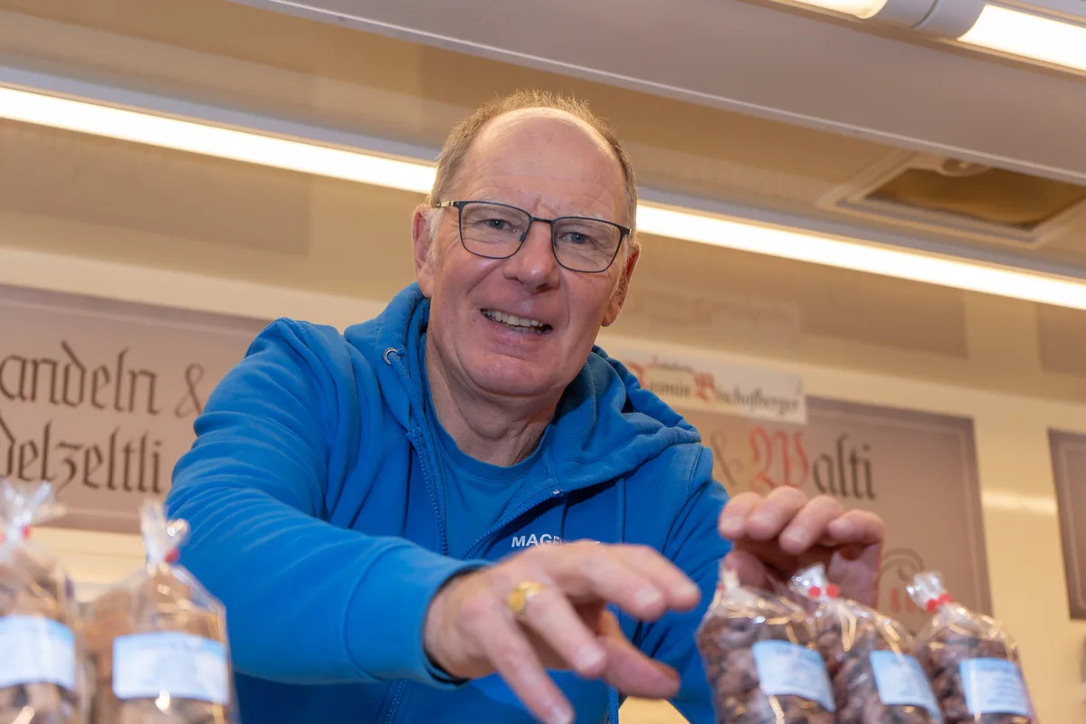 Walti Hanselmann sortiert Säcke mit gebrannten Mandeln. Er trägt eine blaue Jacke.