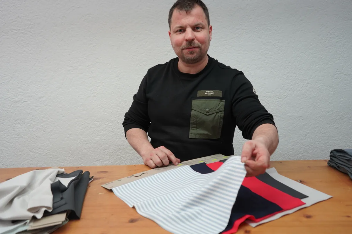 Urs Schellenberg zeigt Musterstoffe aus rezyklierter Baumwolle.
