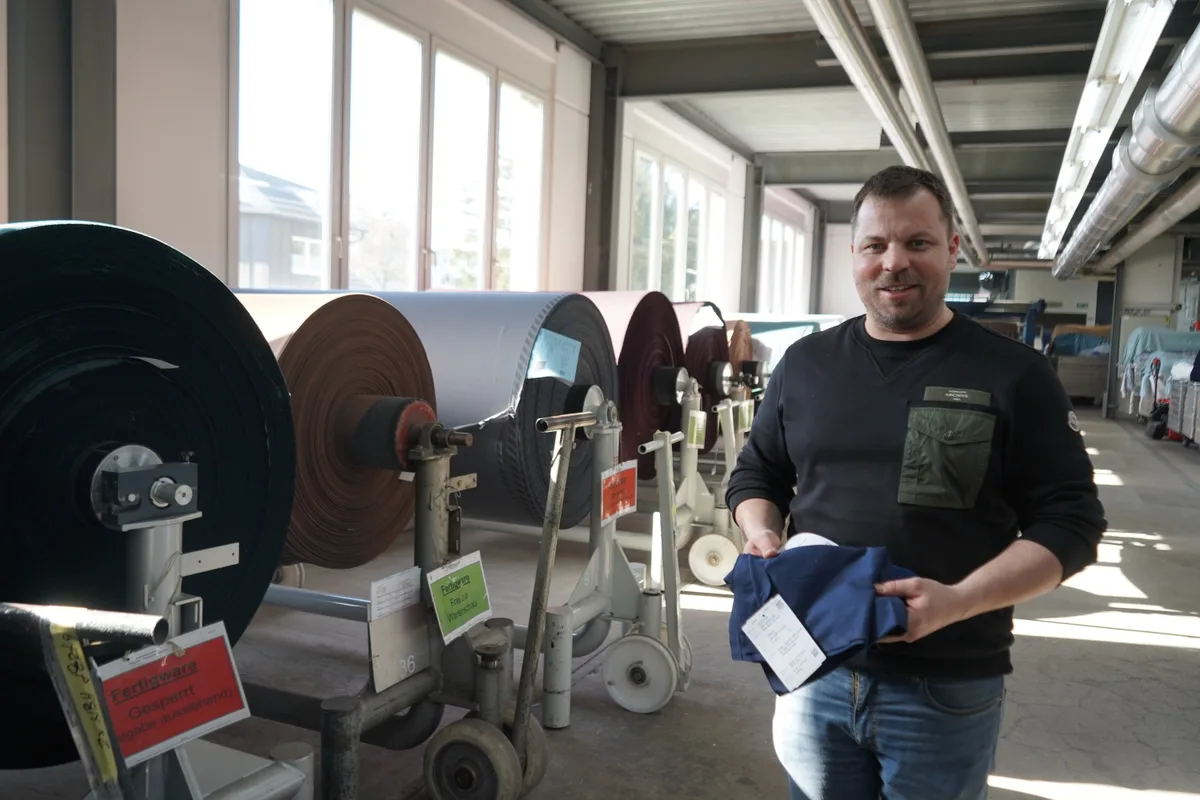 Urs Schellenberg zeigt Musterstoffe aus rezyklierter Baumwolle.