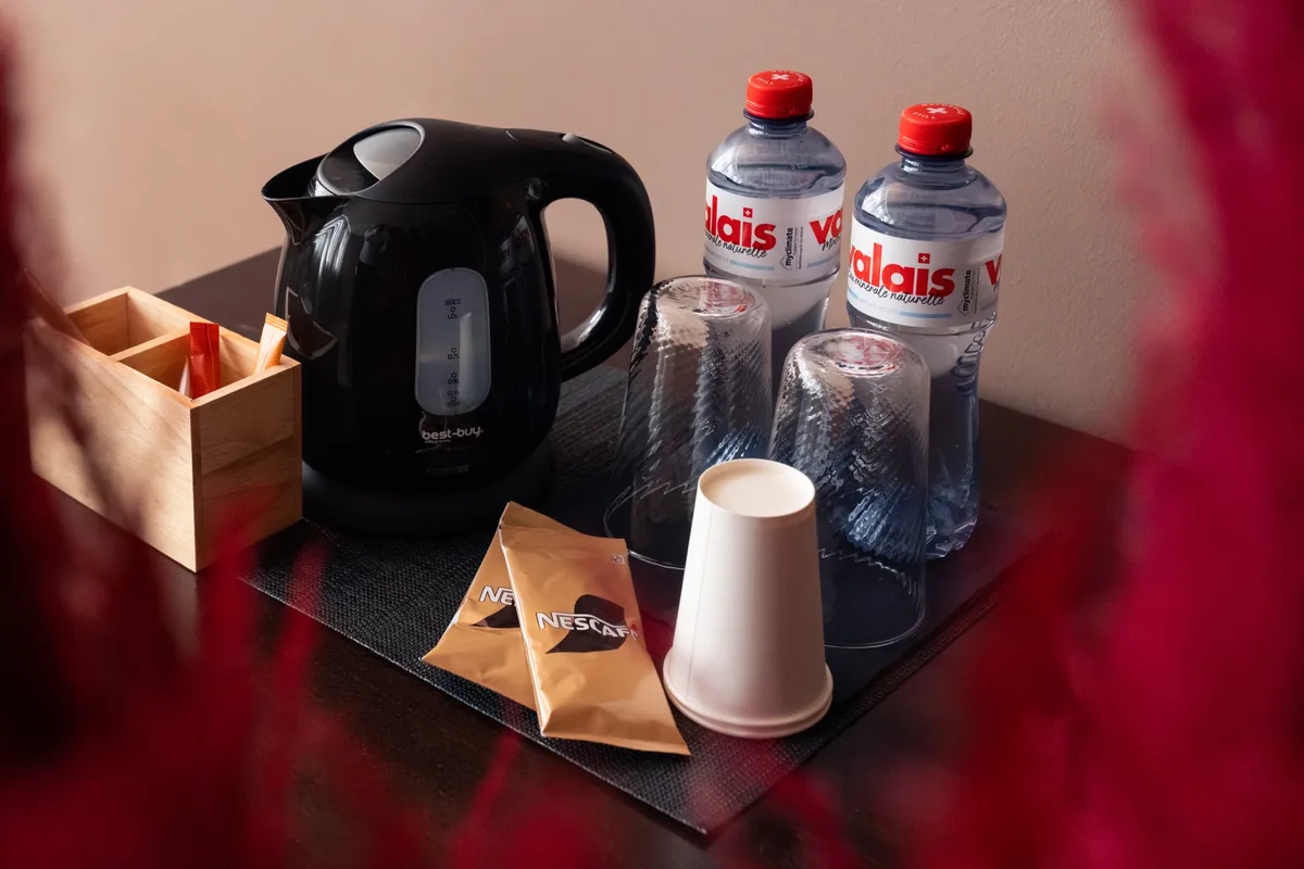 In jedem Zimmer hat es einen Wasserkocher. Ein schwarzer Wasserkocher und zwei Mineralwasserflaschen.