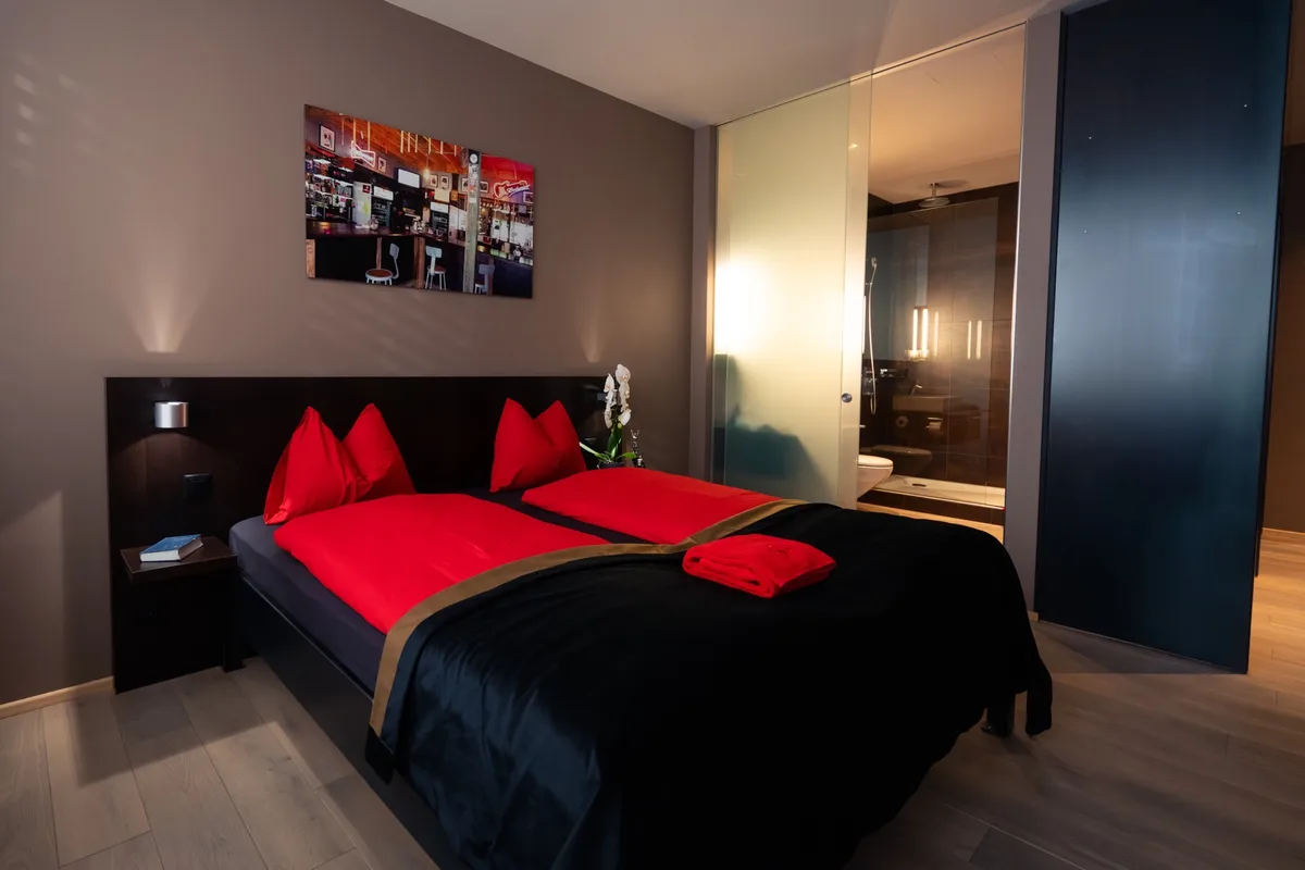 Das Farbkonzept in den 20 Zimmern wird von Schwarz und Rot dominiert. Blick in ein Zimmer im Hotel «Quers Inn». Man sieht ein Bett mit schwarz-roter Bettwäsche.