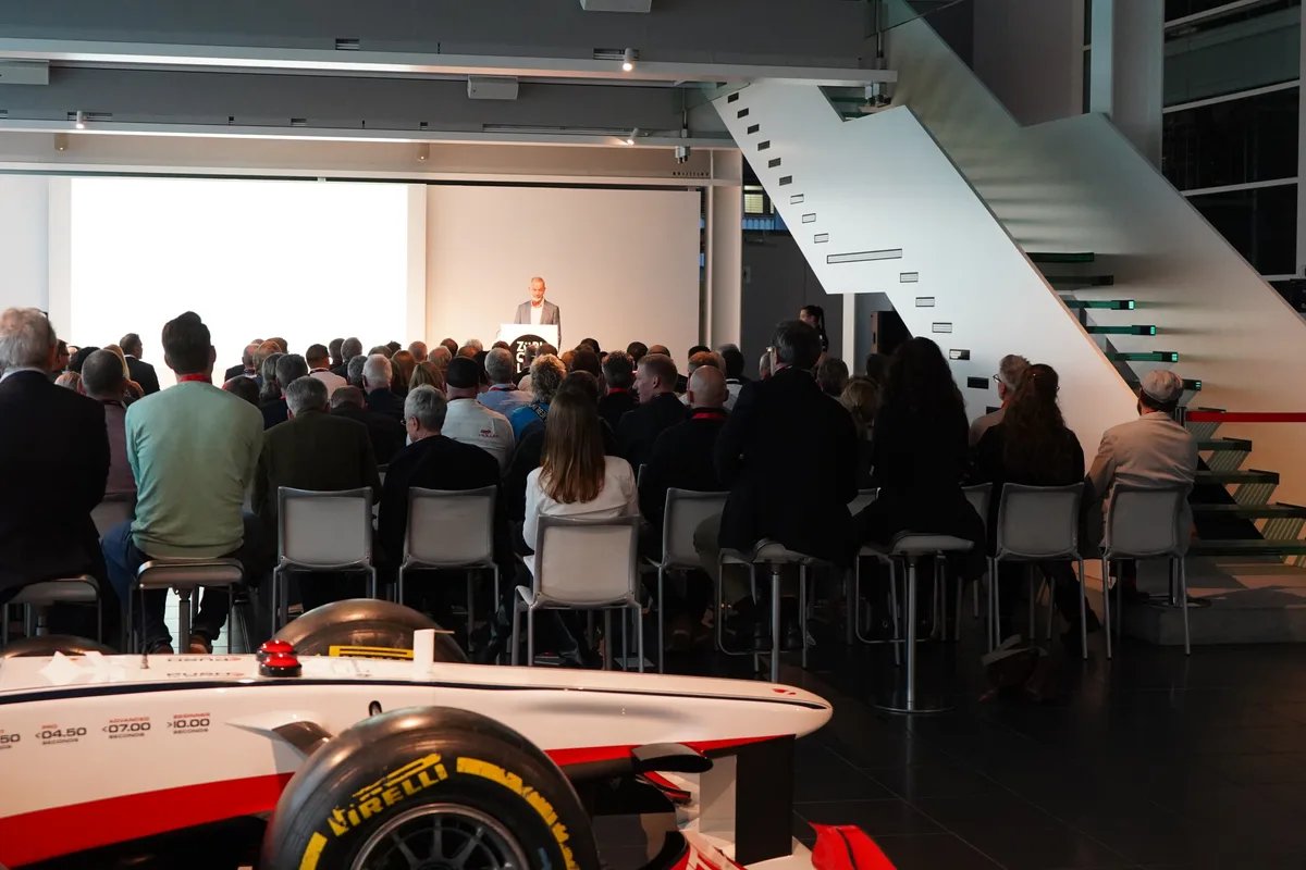 Menschen in einem Saal hören einem Referenten auf der Bühne zu.