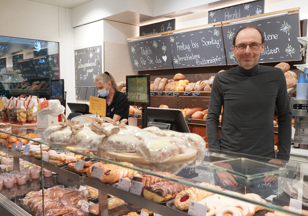 Ein Mann steht hinter der Ladentheke einer Bäckerei.