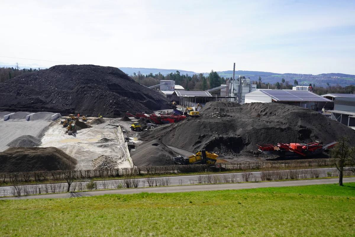 Graue Hügel aus Ausbauasphalt türmen sich auf.