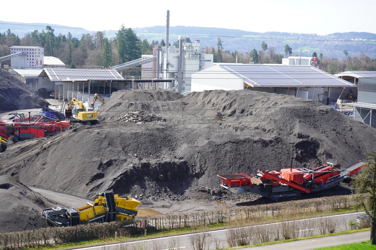 Graue Hügel aus Ausbauasphalt türmen sich auf.