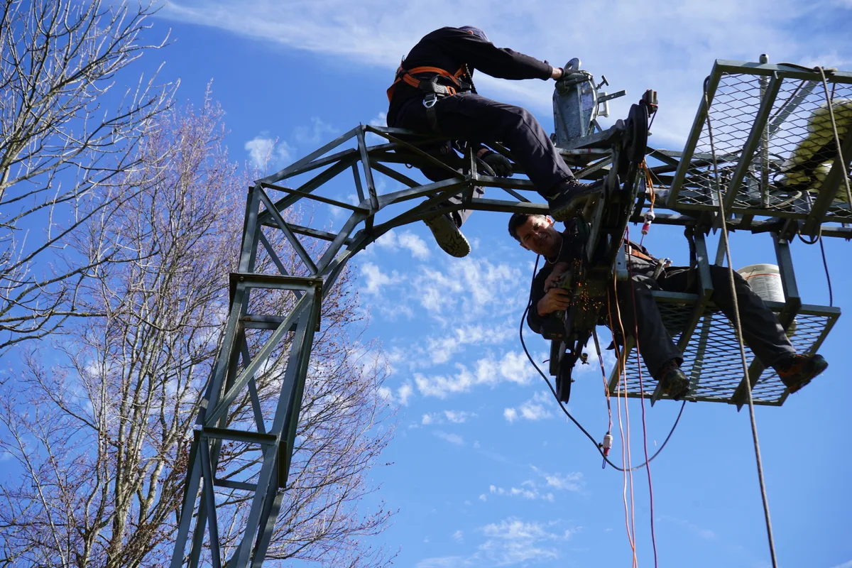 Revisionsarbeiten am obersten Mast des Skilifts Ghöch in Bäretswil. Zwei Männer sitzen auf einem Mast.