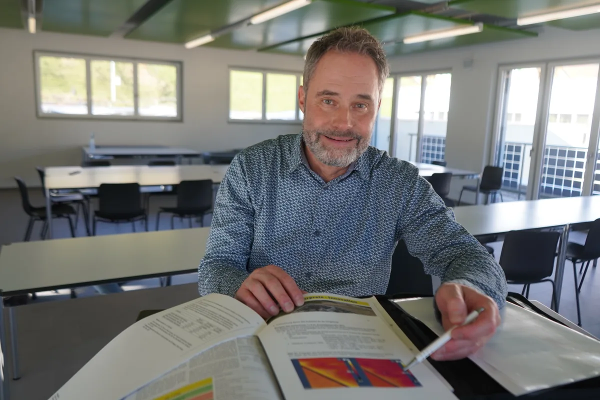 Daniel Diggelmann sitzt an einem Tisch und zeigt mit dem Kugelschreiber auf eine Grafik vor ihm.