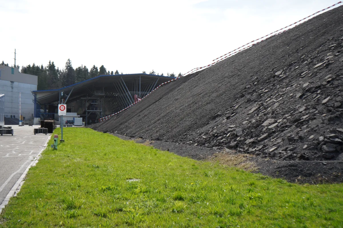 Graue Hügel aus Ausbauasphalt türmen sich auf.